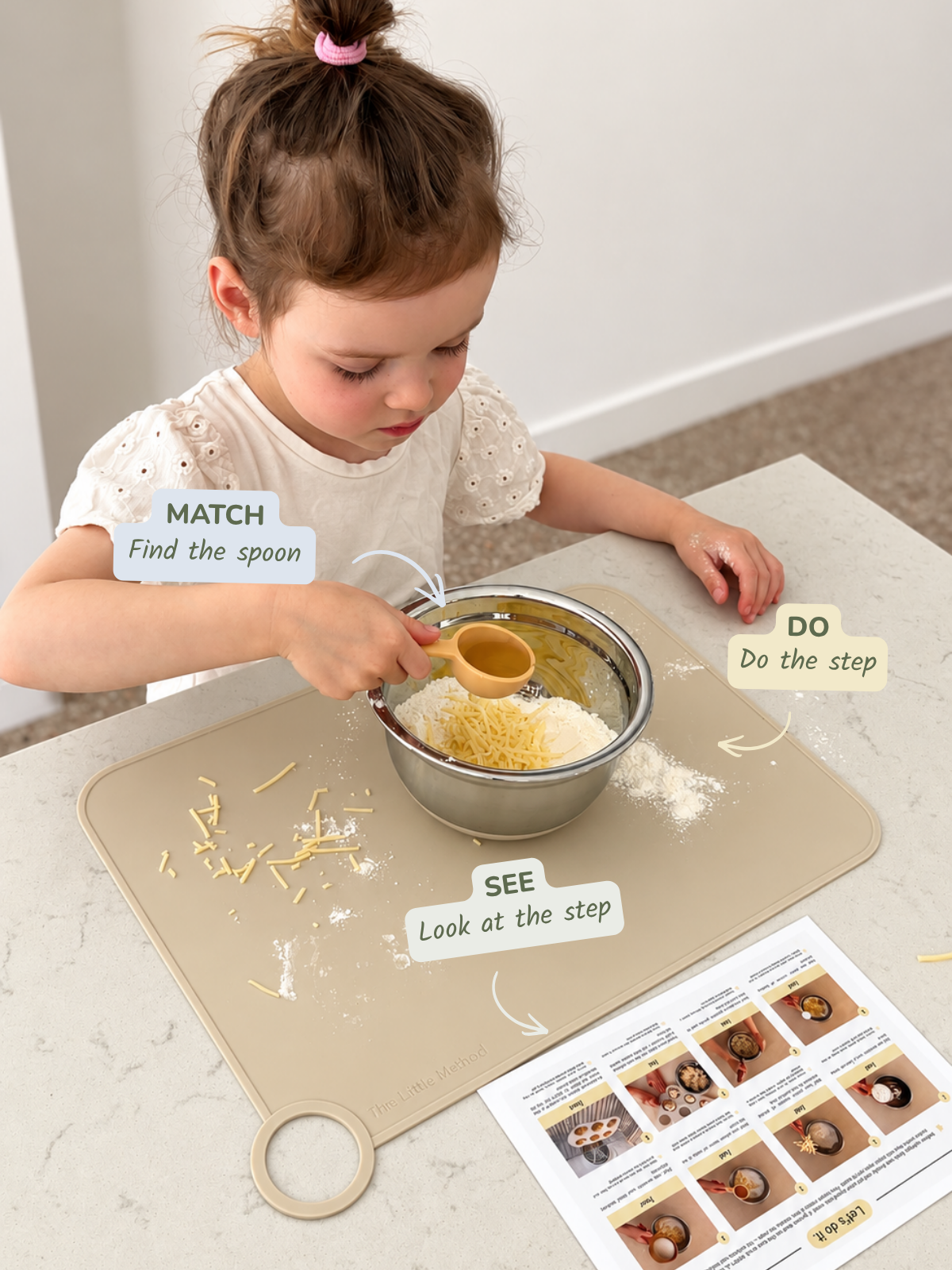 A child using The Little Method recipe card and measuring spoon to follow a cooking step, with SEE, MATCH and DO callouts visible