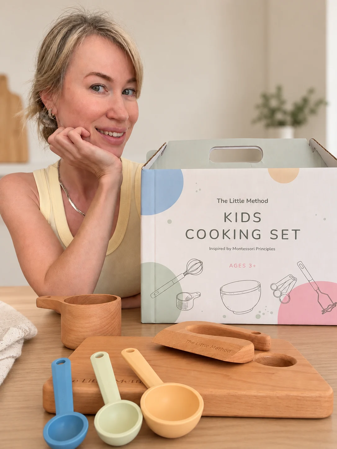 Irina, founder of The Little Method, beside The Little Method kids cooking set box and wooden tools on a kitchen bench